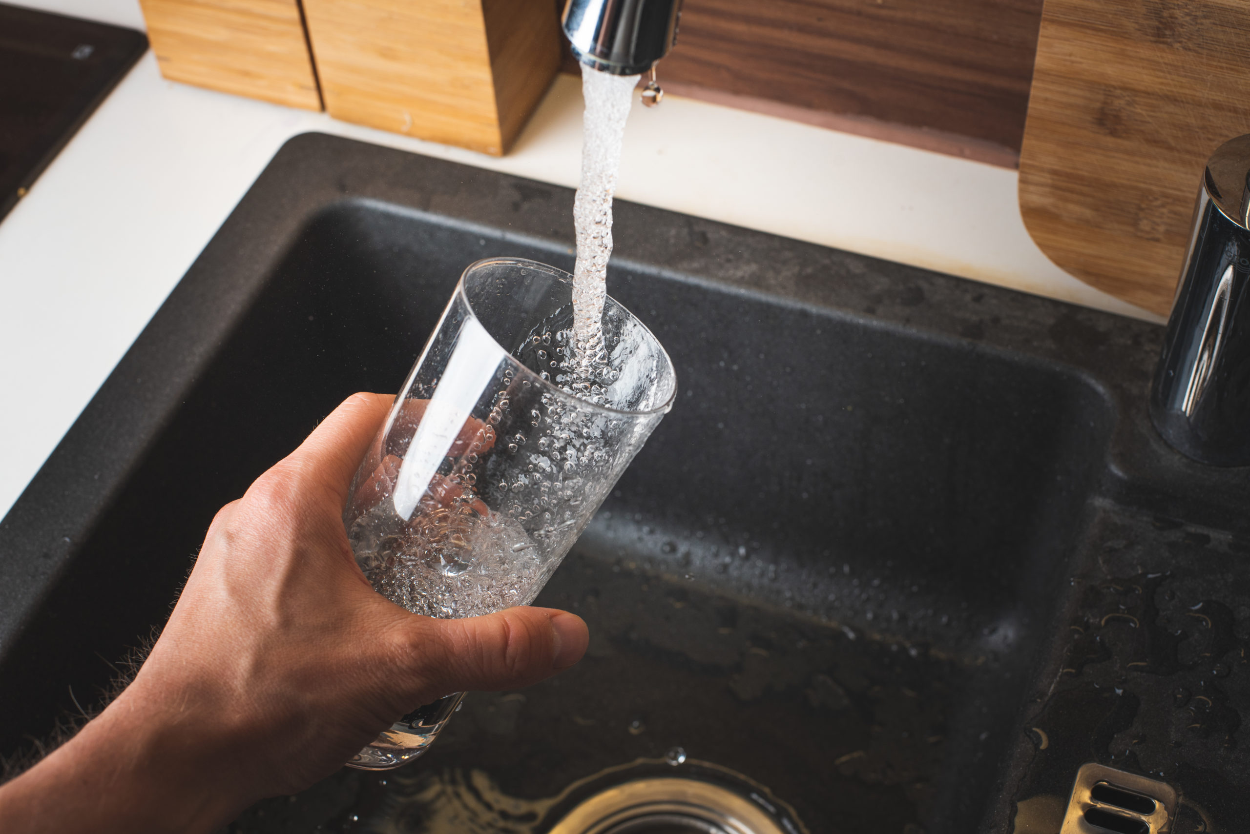 person drinking water from kitchen faucet